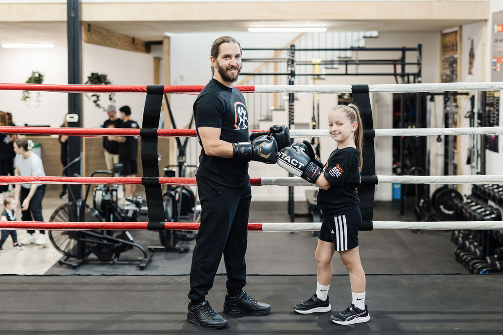 Une jeune boxeuse et son entraîneur se rejoignent avec leurs gants dans le ring
